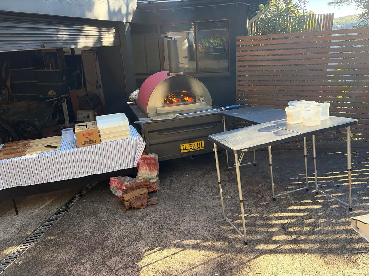 The red wood-fired oven alight on its trailer, set up and ready to serve